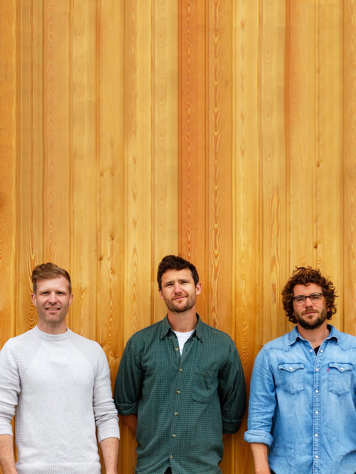 coast creative founders dave jones, nick williams and luke white stood against a plain wooden wall