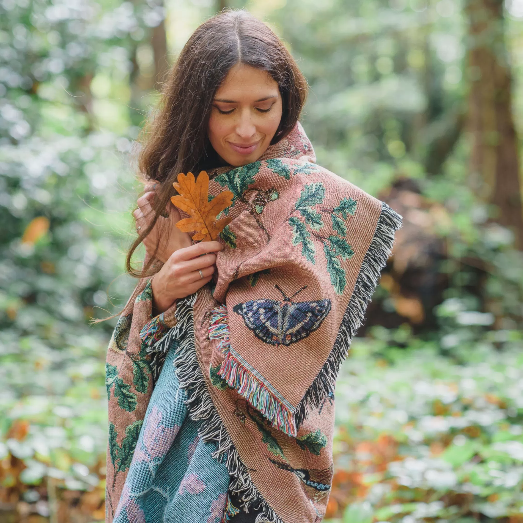 Ria Mishaal from Arcana wrapped in Wild Oak blanket holding an oak leaf
