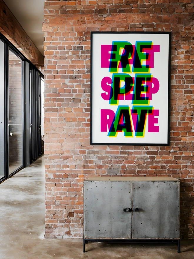 A colourful neon typographic giclée poster with the words "Eat Sleep Rave Repeat" hangs on a brick factory apartment. An ideal gift for an old raver!