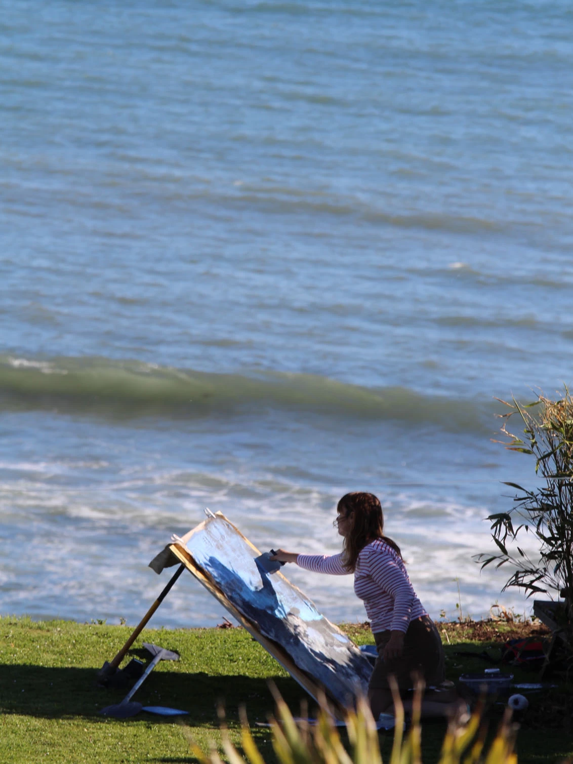 claudia painting at the bottom of her garden facing the sea