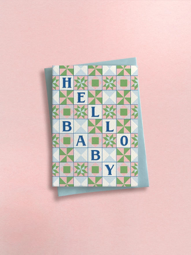 Greeting card designed by Flora Fricker in Bristol, UK. Hello baby illustrated design, vintage quilt in pink blue and yellow.