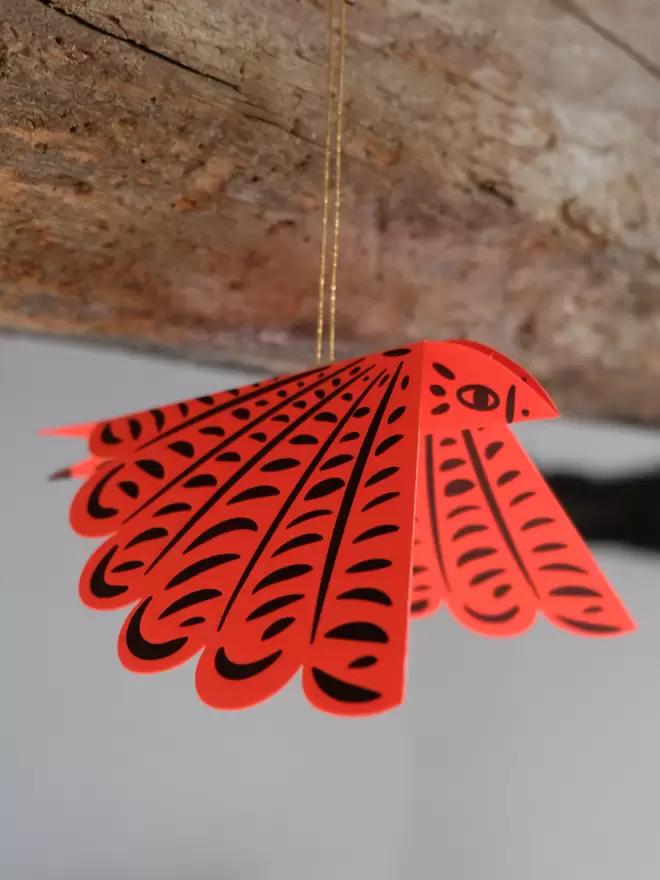 Electric red letterpress bird hanging from gold thread.