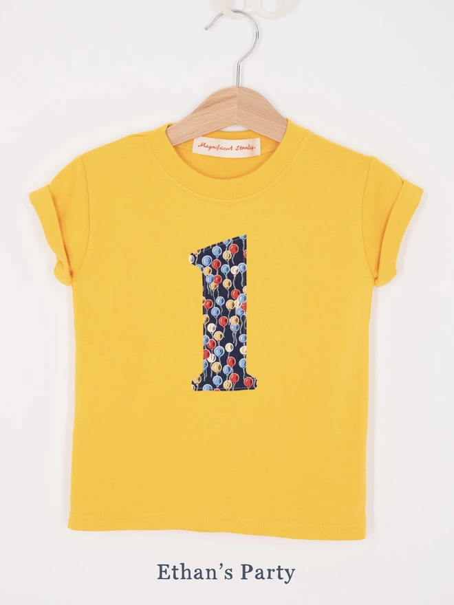 a yellow t-shirt with a balloon number 1 on front