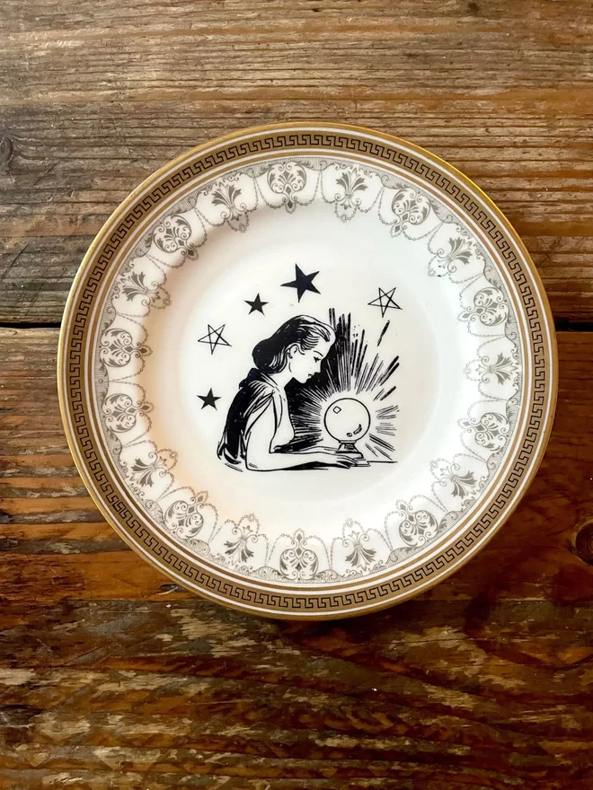 vintage plate with an ornate border, with a printed vintage illustration of a fortune teller in the middle