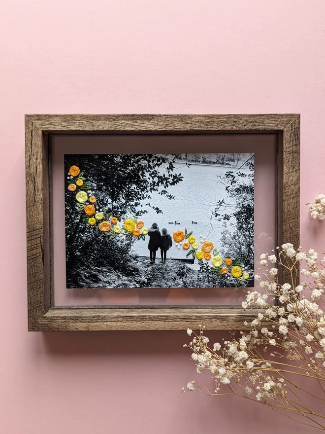 B&W photo of girl with yellow flowers embroidered around them in frame