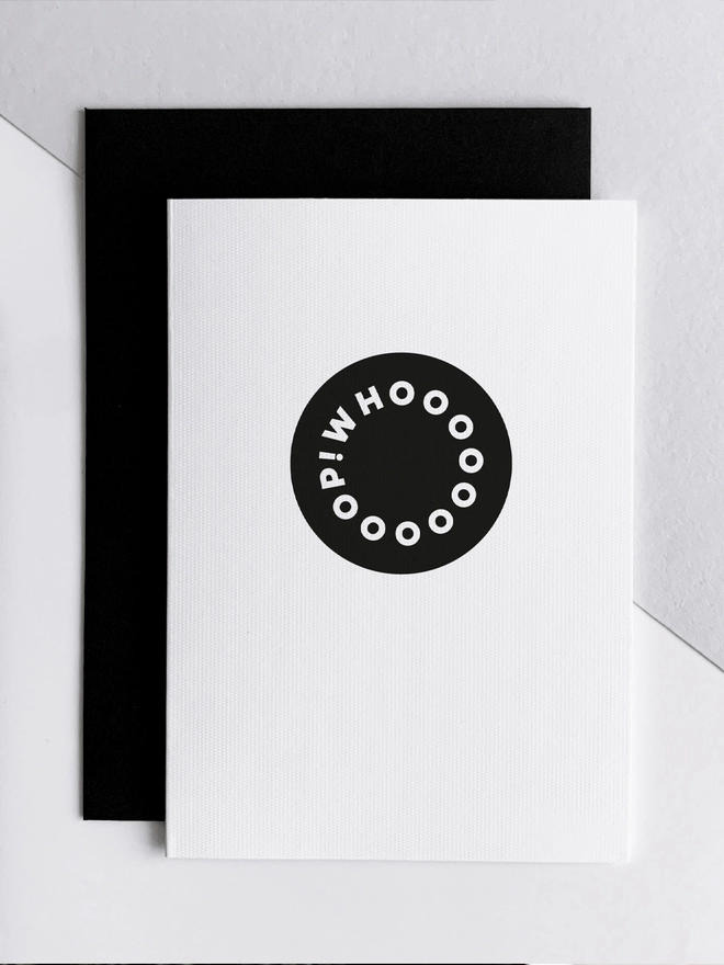 Whoop! Good News Card overlapping a black envelope on a white background.