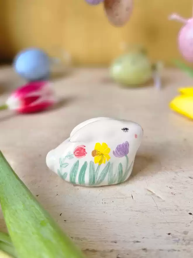 little ceramic bunny with handpainted spring flowers around the body of the rabbit.