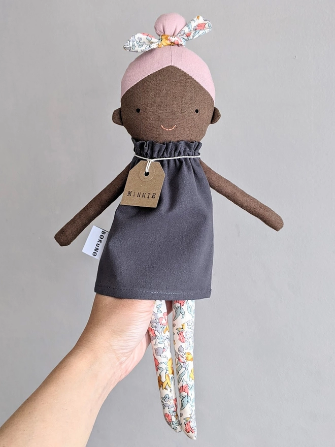 fabric girl doll with dark skin and pink hair