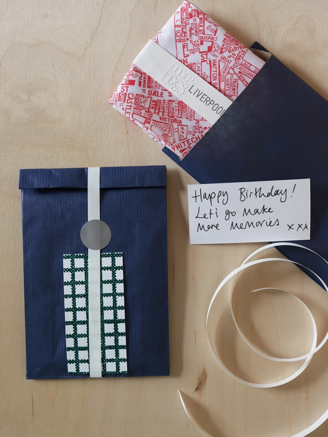 optional gift wrap example showing Liverpool hankie in navy paper with white ribbon