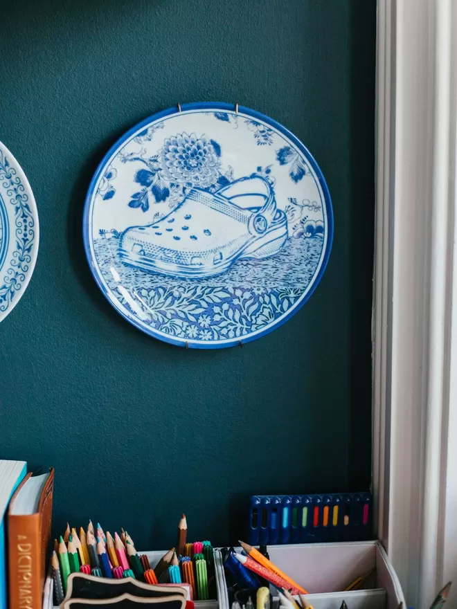 Croc Delft Style China Plate seen in a bedroom with stationary below.