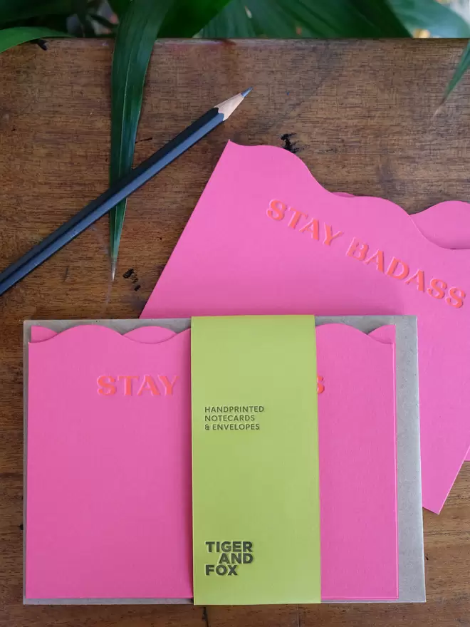 Stay Badass letterpress printed in orange ink on bright pink (magenta) wavy cut notecards with recycled kraft envelopes.