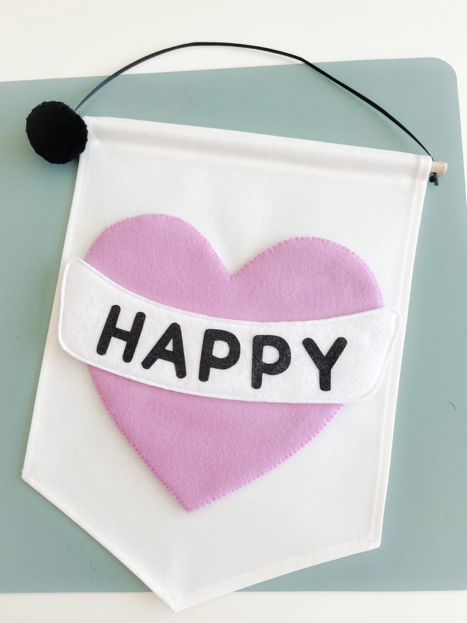 Close up of white banner with a lilac heart saying the word happy