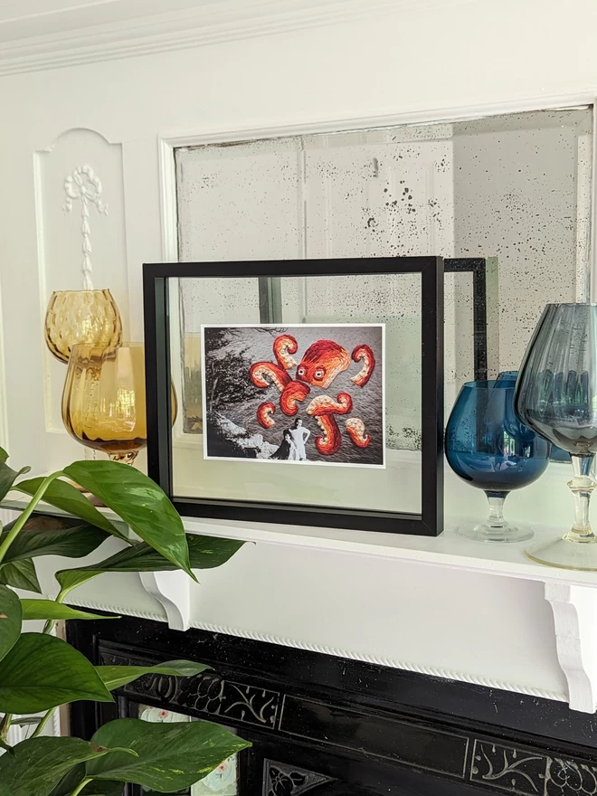 B & W photo of couple with embroidered octopus behind them, framed on mantlepiece
