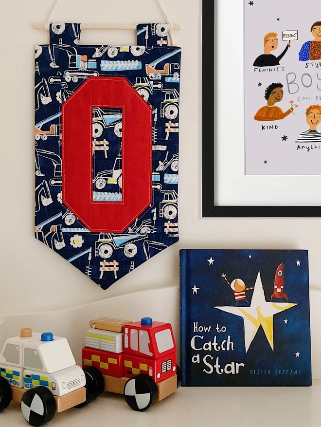 Cooper & Fred Personalised Quilted wall-hanging seen with a mechanical fabric and a red letter 'O.'