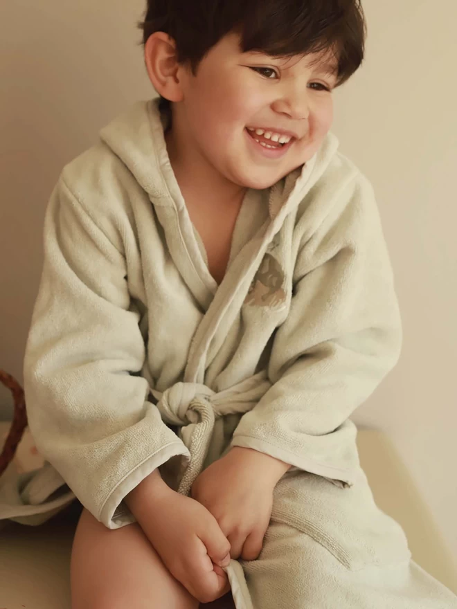 A boy wearing a towelling robe with frog embroidery