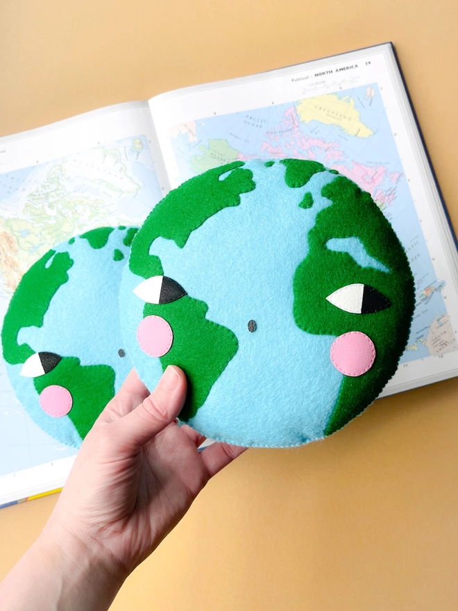 A Earth wall decoration being held over a world map book