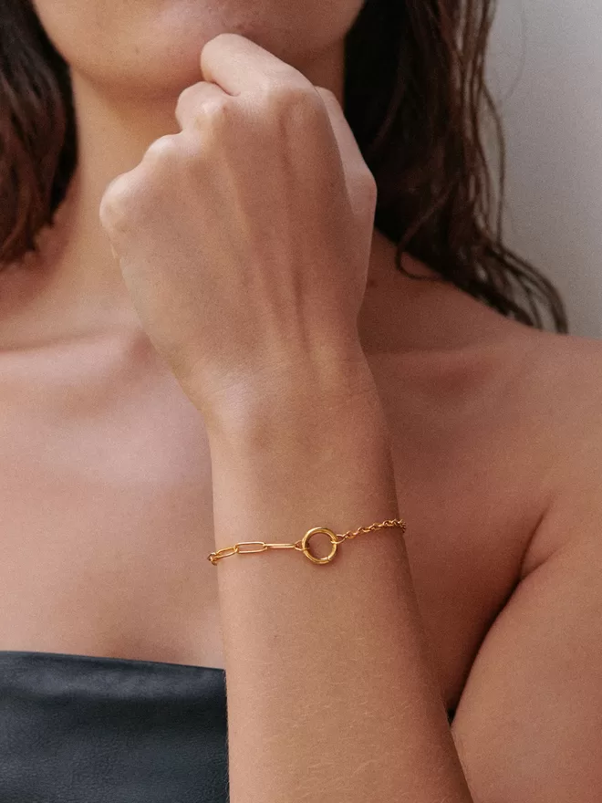 woman wearing gold bracelet with paperlink chain on one side and a cable chain on the other