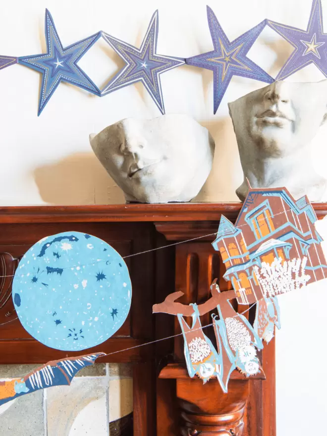 Star shapes, half-head busts and haunted house garland hanging on fireplace