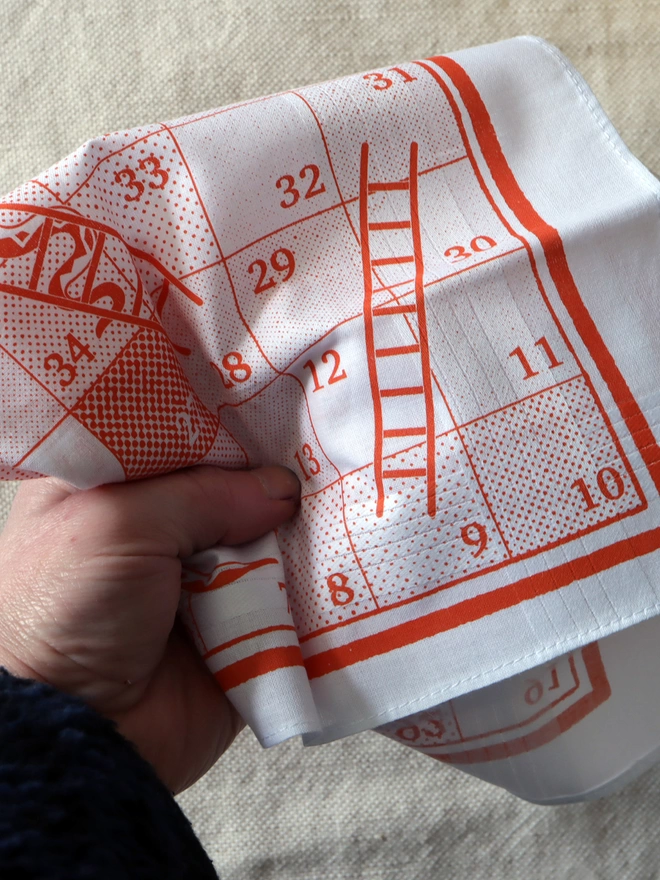 Detail of a Mr.PS Snakes & Ladders hankie held in a hand