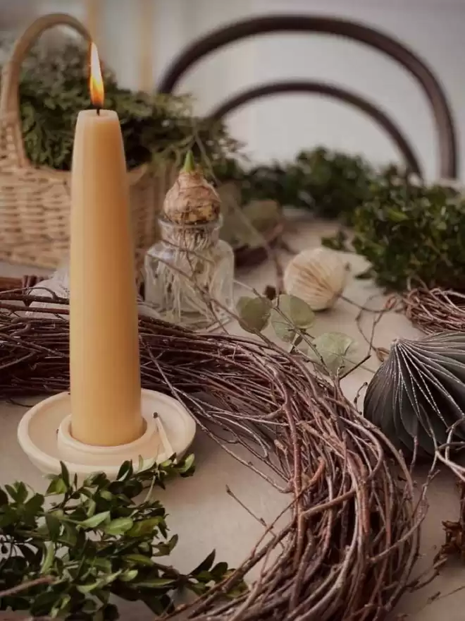 Pearl White candle holder with giant stubby beeswax candle. Surrounded by twig wreath, spring bulbs and basket of moss
