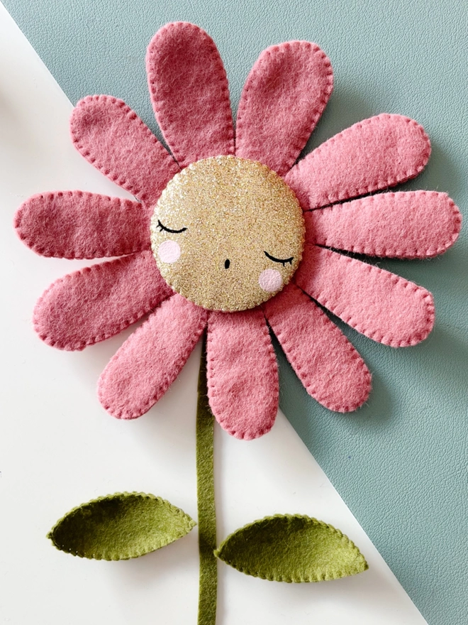A pink Daisy with a painted sleepy face