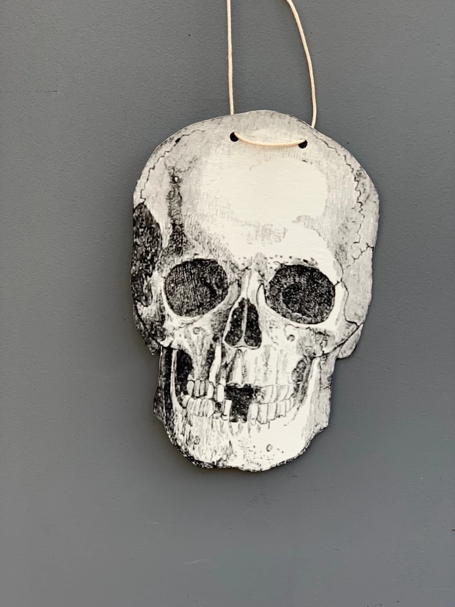 Close up of a paper cut skull against a grey painted wall