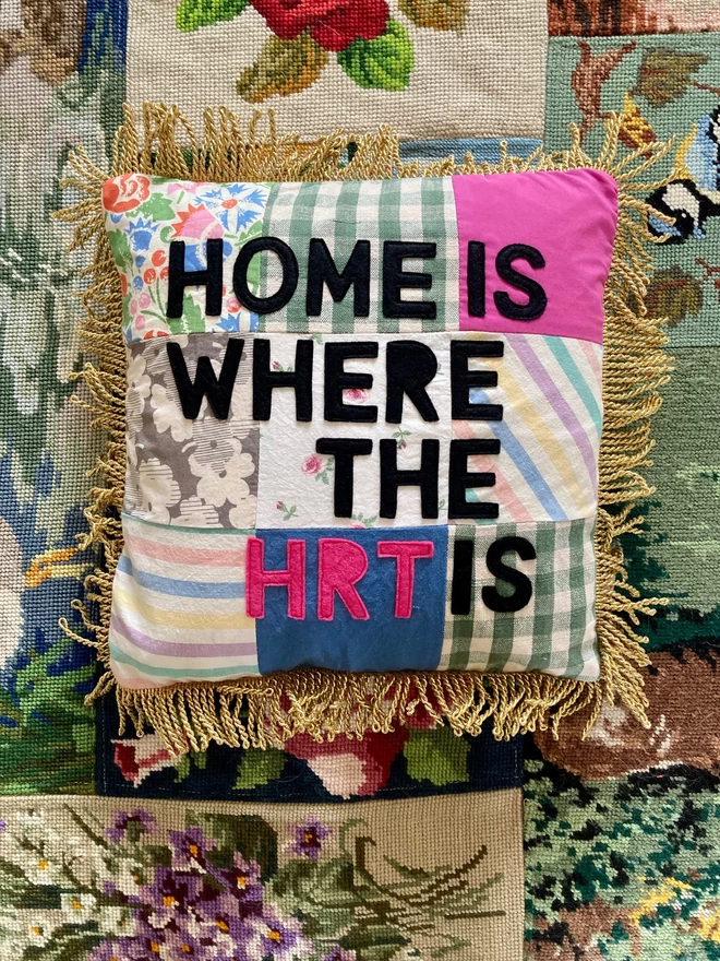 Patchwork cushion with 'Home is where the HRT is' appliqued on, on a tapestry background