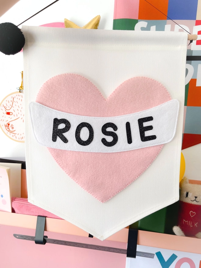 Pink heart banner on a cream background with the name Rosie in black writing