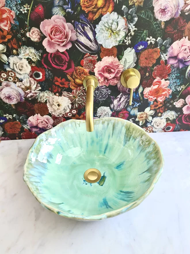 Handcrafted ceramic bathroom basin in a turquoise green blue glaze, hand-crafted sink, pottery basin, wc, bathroom, ensuite, modern bathroom, photographed against green art deco wallpaper with gold taps, homeware, interiors, front view