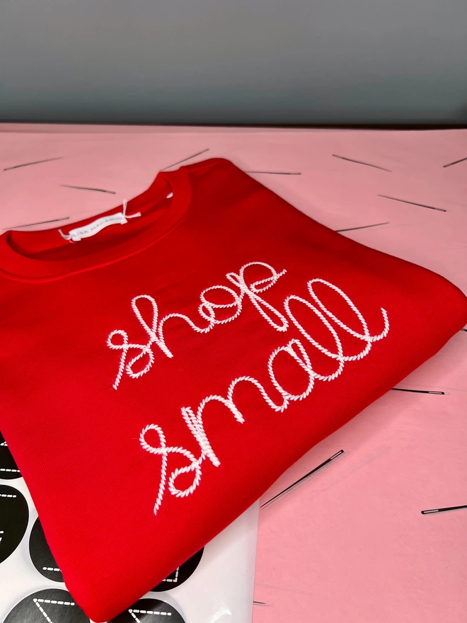A folded red sweatshirt embroidered with shop small in white