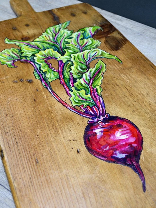Close up of a wooden chopping board with handpainted design of a beetroot