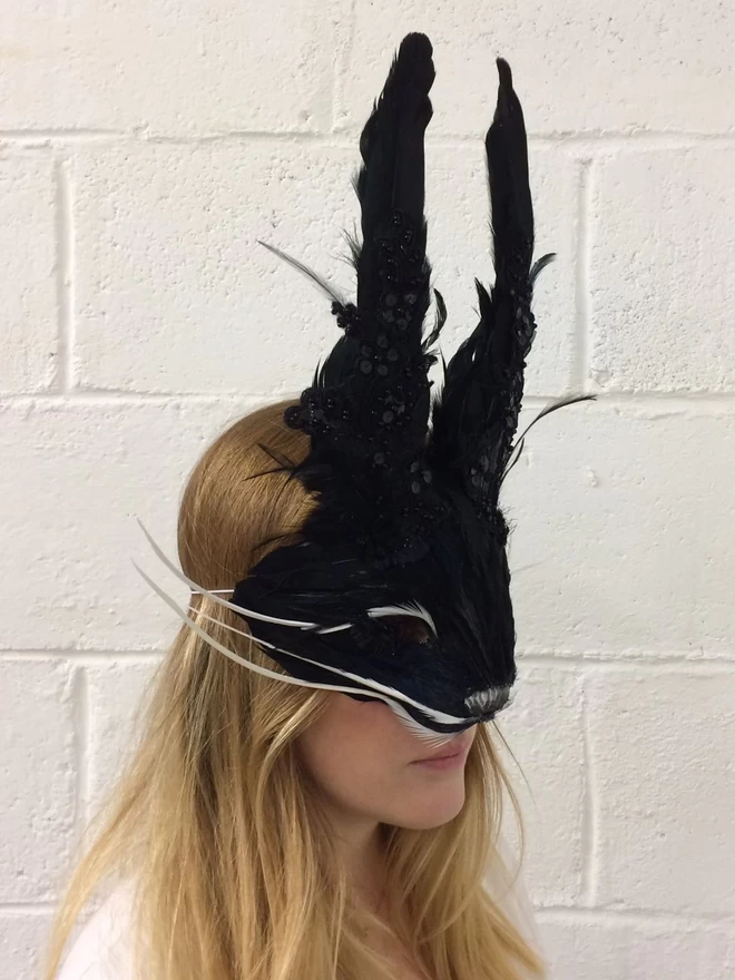A woman wearing a luxury black embellished rabbit party mask down over her face