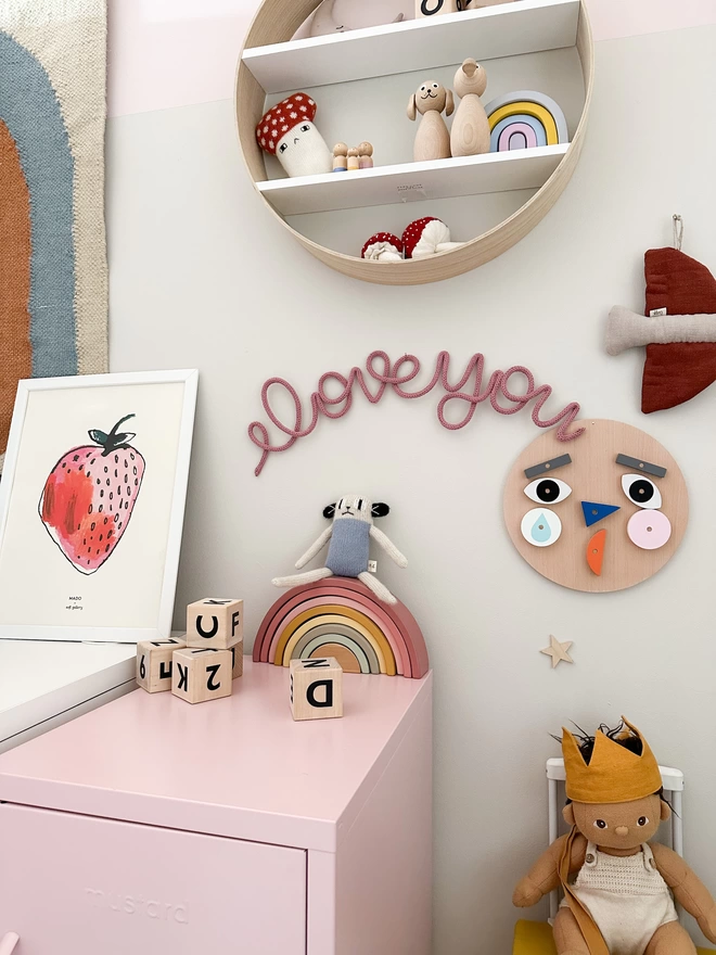 "I love you" in a pink dusty rose colour hanging up on a girls bedroom wall. 