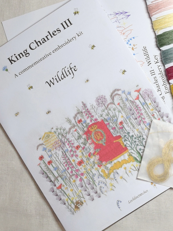 King Charles III Embroidery Kit of Wildlife, The instruction pamphlets front cover with some kit contents showing such as the gold bar and thread card.