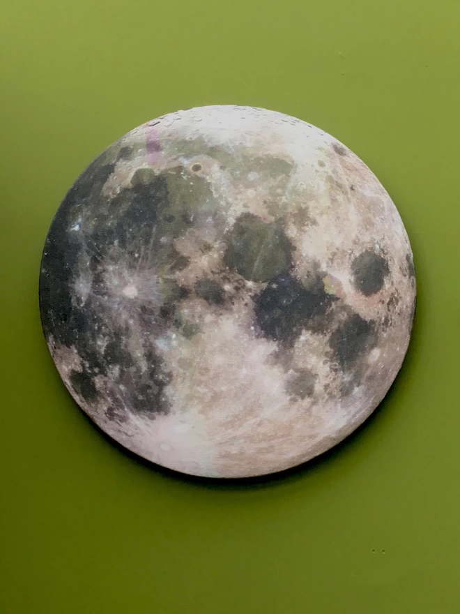 A full moon fabric wall art  on a green painted wall