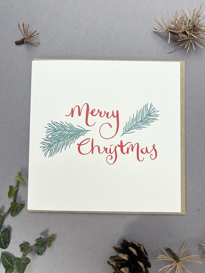 Red letterpress printed Merry Christmas with sprigs of pine around it