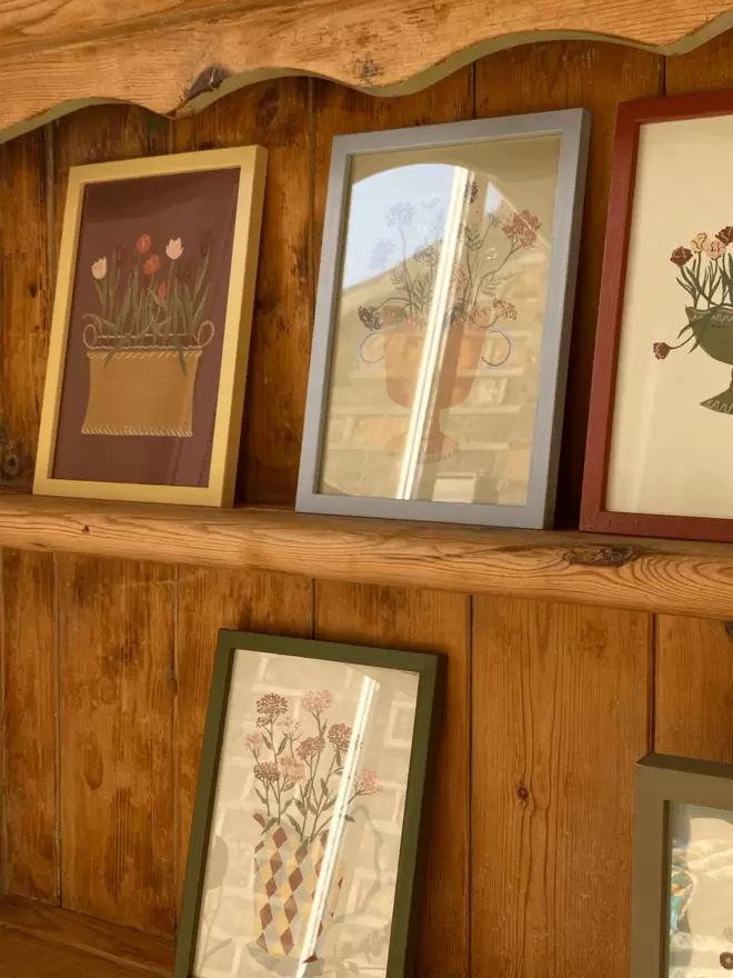 prints of parrot tulips and queen annes lace in colourful framed prints on antique wooden shelving. 