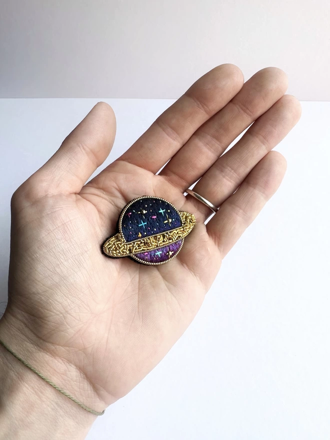 Planet brooch in hand