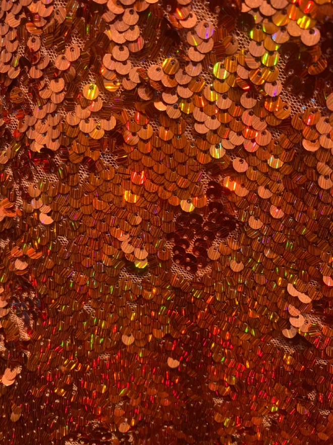 Close up detail of Orange Rust Holographic Sequin V-neck Kaftan Gown.