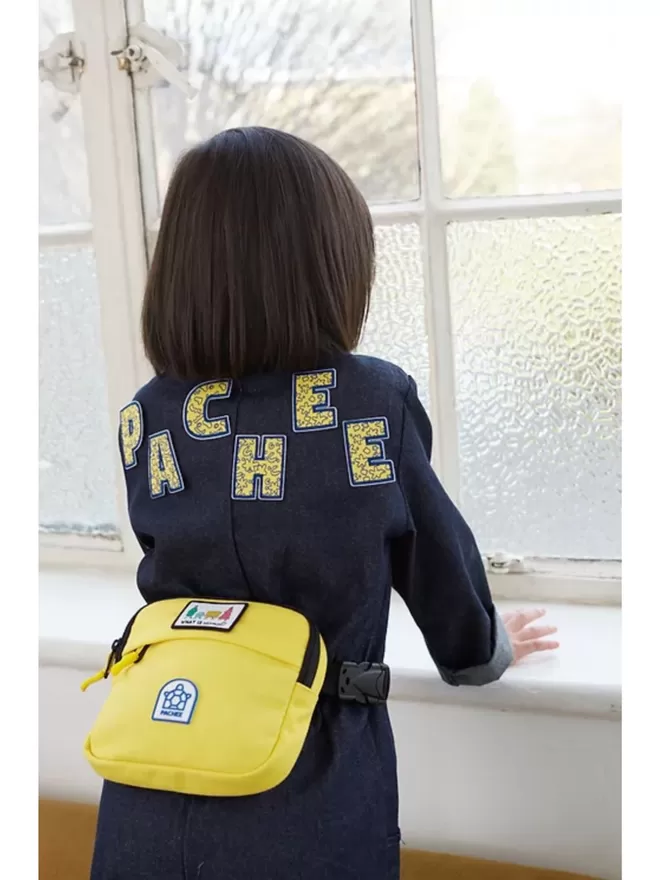 'PACHEE' written using the alphabet patches on the back of a denim jumpsuit.