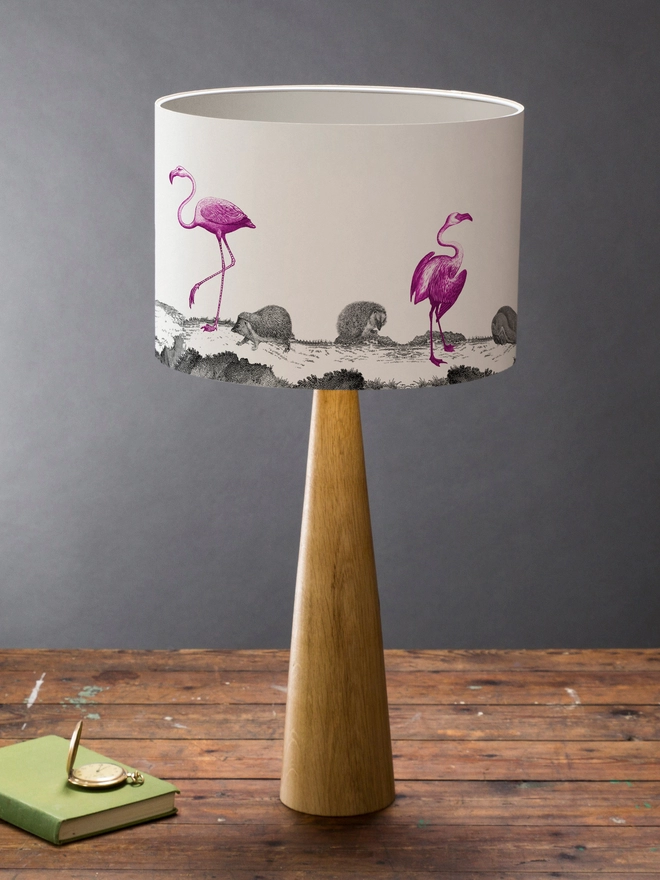 Drum Lampshade featuring pink flamingos and hedgehogs on a wooden base on a shelf with books and ornaments