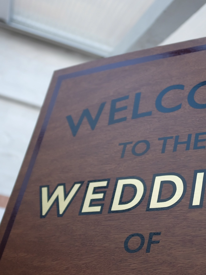 Close up of the top left corner of handpainted gilded welcome wedding sign. 