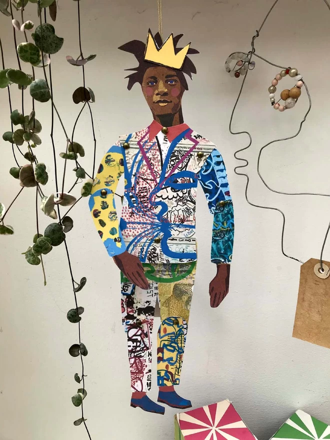 Lifestyle shot of Basquiat wearing a crown and dangling next to a plant