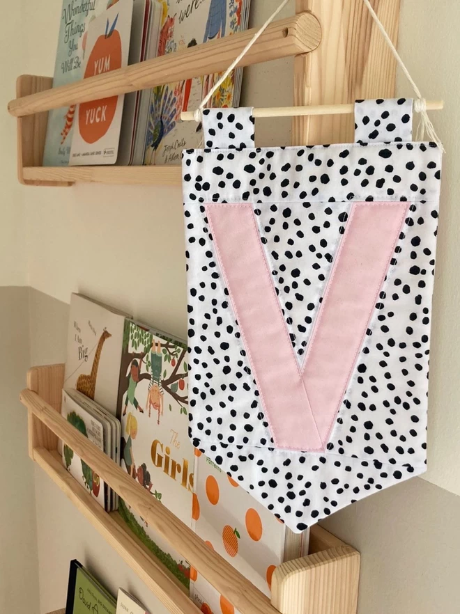 Cooper & Fred Personalised Quilted Wall Hanging seen with a spotted fabric and a pink 'V'.