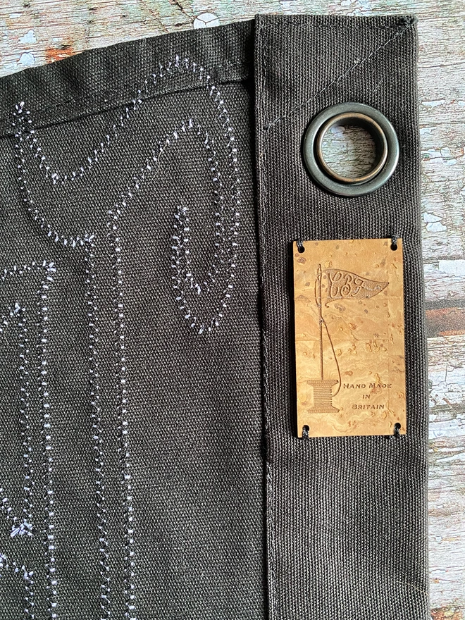 Detail of the back of a Trick or Tequila black pennant flag. It shows the stitching on the back of the pennant, a hanging eyelet and cork label.