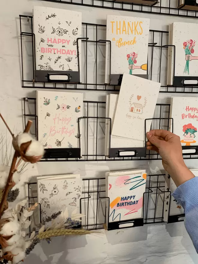 Hand picking out a card from a selection of cards in a wire rack