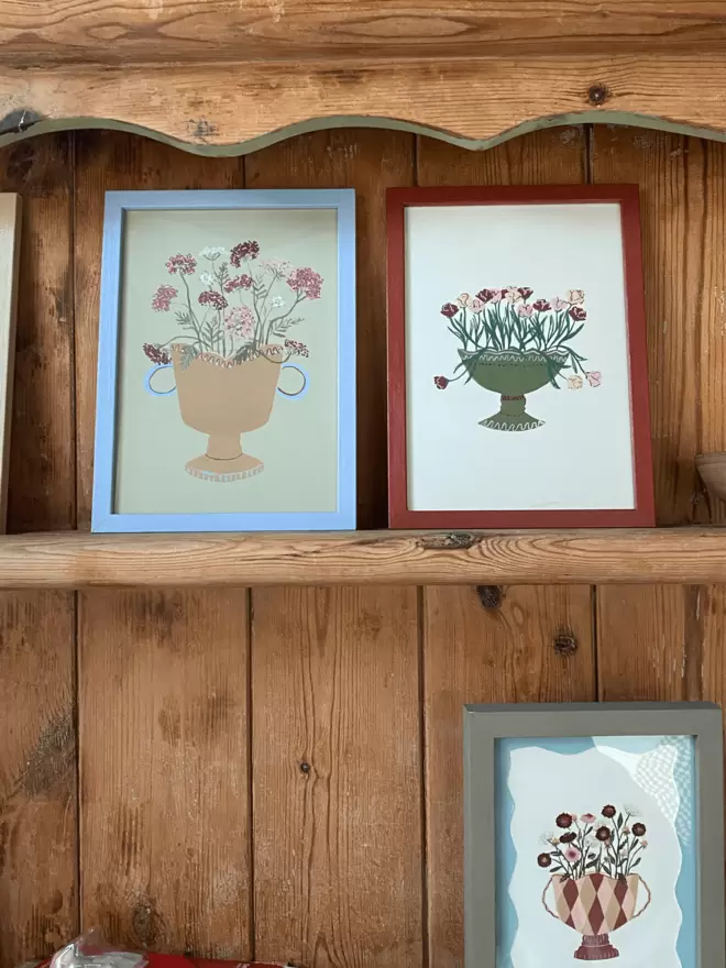 prints of parrot tulips and queen annes lace in colourful framed prints on antique wooden shelving. 
