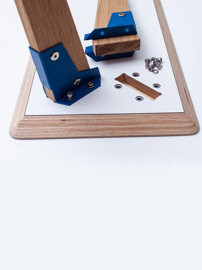 underside of a piece of modpop furniture showing an oak leg in a blue coloured bracket next to the slot it fits in.