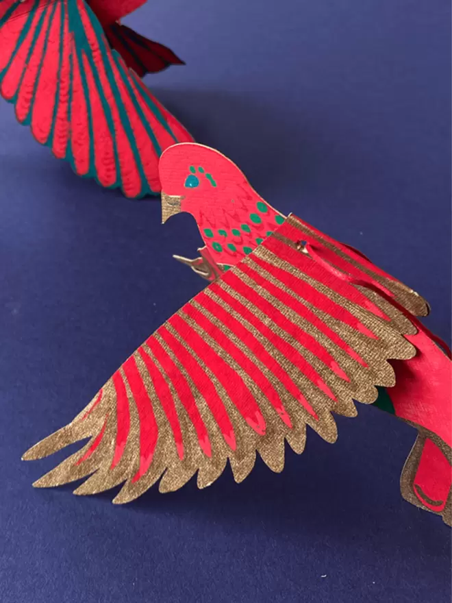 Close up of pink bird paper decoration on a deep purple background