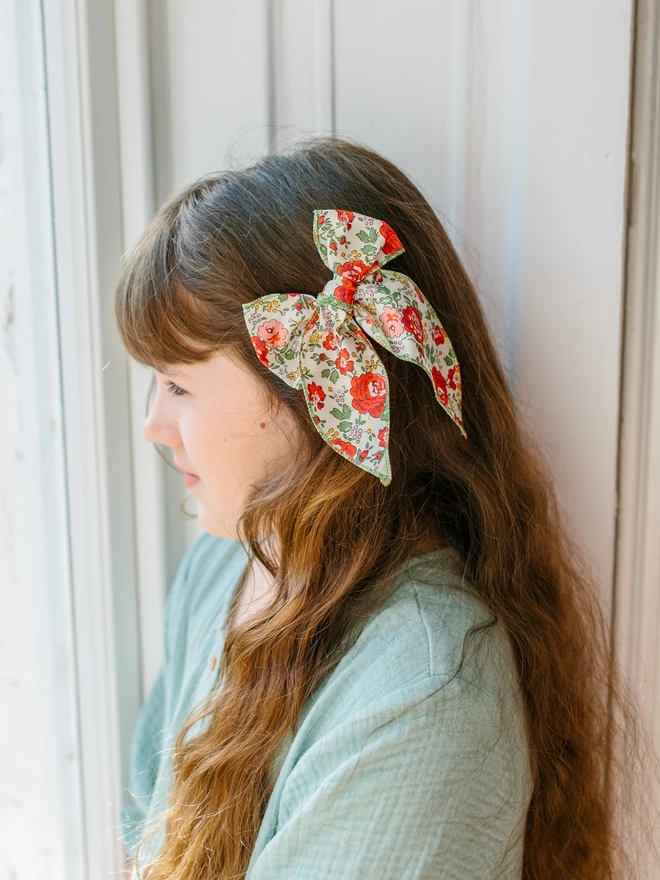 girl with long brown hair wearing  liberty floral bow